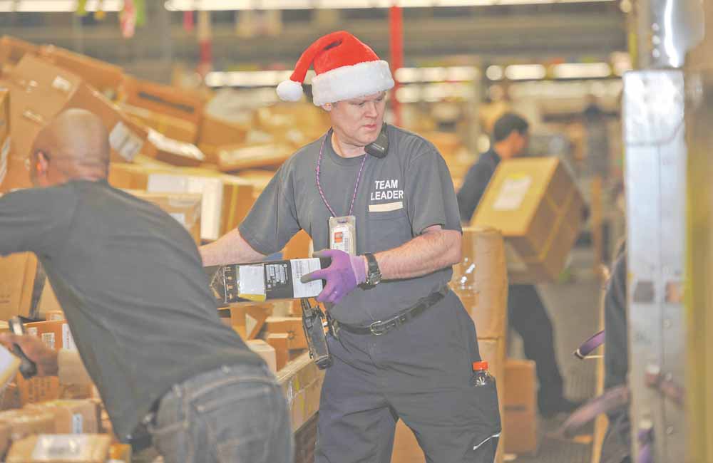 FedEx team leader Mike Almon, in Santa hat, sorts packages Monday with fellow employee Jason Taylor Monday, Dec. 13, 2010 in Anchorage, Alaska. Monday is expected to be the busiest day in FedEx history, with nearly 16 million packages moving on its conveyer belts, trucks and planes. That's up 13 percent from 14.2 million on the busiest day last year, and double what the company handles on a normal day. That jump in shipments bodes well for the nation's retailers, online stores and larger rival UPS, which has its single busiest day next week.