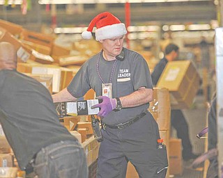 FedEx team leader Mike Almon, in Santa hat, sorts packages Monday with fellow employee Jason Taylor Monday, Dec. 13, 2010 in Anchorage, Alaska. Monday is expected to be the busiest day in FedEx history, with nearly 16 million packages moving on its conveyer belts, trucks and planes. That's up 13 percent from 14.2 million on the busiest day last year, and double what the company handles on a normal day. That jump in shipments bodes well for the nation's retailers, online stores and larger rival UPS, which has its single busiest day next week.