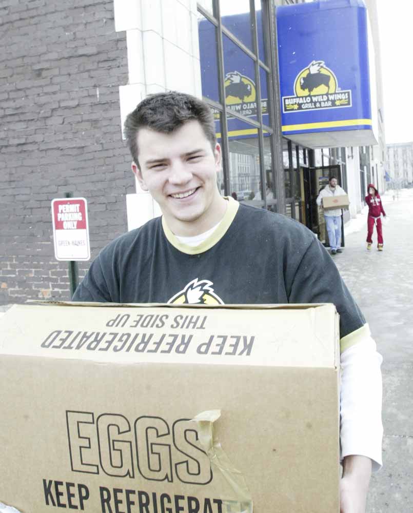 Brad Yaskowitz, an employee of Buffalo Wild Wings restaurant in downtown Youngstown, hauls eggs donated by his employer and Save-A-Lot stores to needy families. The restaurant here and in Niles passed out food Wednesday in Mahoning and Trumbull counties.