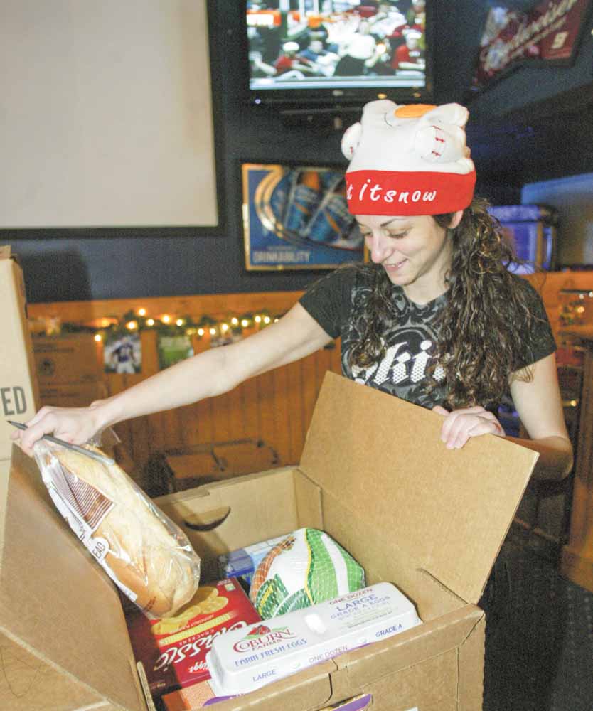 Kristen Calo, an employee of Buffalo Wild Wings restaurant in downtown Youngstown, makes sure this food box is full. Buffalo Wild Wings and Save-A-Lot stores teamed up to give out the food boxes to 200 needy families Tuesday here and in Niles.