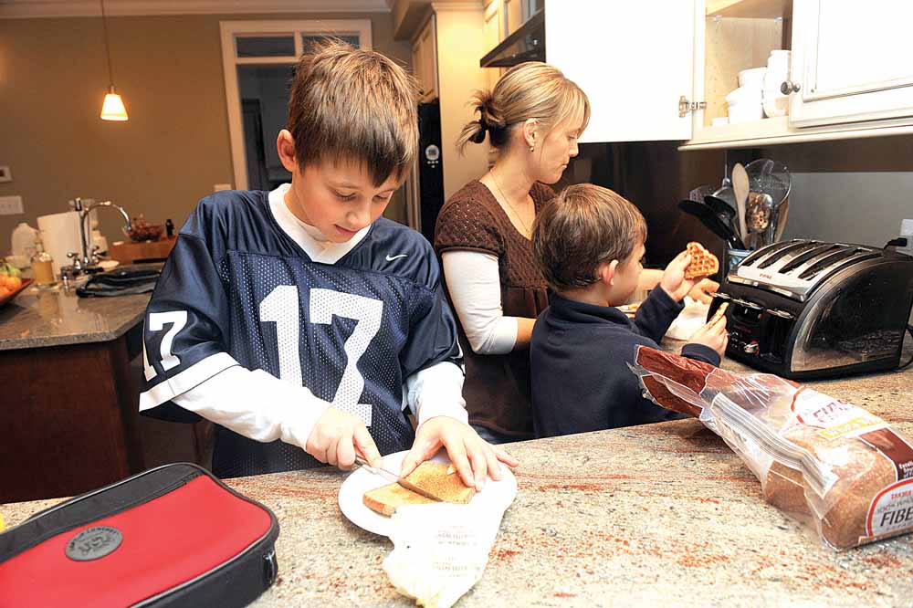 Ben DeRocco, 10, puts butter on his whole wheat bread as mom Susanna DeRocco helps Griffin, 7, toast waffles at their home in Baltimore, Maryland, on December 15, 2010. 