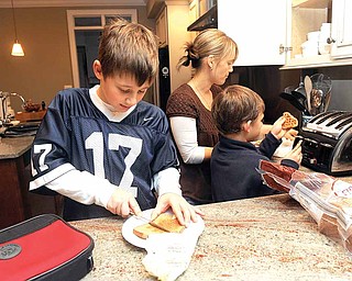 Ben DeRocco, 10, puts butter on his whole wheat bread as mom Susanna DeRocco helps Griffin, 7, toast waffles at their home in Baltimore, Maryland, on December 15, 2010. 