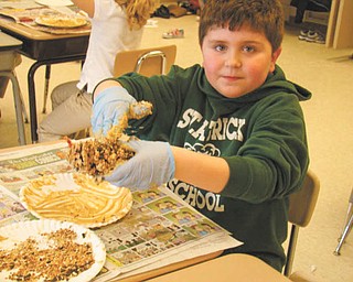 Food for the hungry: Students in Mrs. Leonard’s second-grade class at St. Patrick School in Hubbard regularly donate canned goods, clothing and money to help those in need. Recently they decided also to help their feathered friends during the winter months by providing food for the hungry birds. Jeffery Hazy, one of the students who participated in the hands-on project, is shown as he coated one of the large pinecones with peanut butter before rolling it in bird seed. Once the pinecones were prepared, they were hung in trees as a holiday treat for the birds.