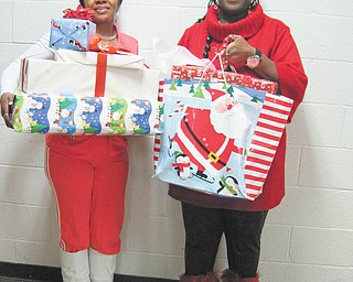 If you wish upon a star: The YWCA’s Wish Upon a Star gift-giving project, in partnership with community groups and individuals, collected new toys, books and games that were distributed to more than 80 homeless and low-income children in the YWCA housing program. Holding an armful of gifts she received for her five children is, at left, Lillian Peoples, who has a disability that prevents her from working. Residents in the Transitional Housing Program at the YWCA, her family is one of the 41 families helped through the Wish Upon  a Star project. Carrying some of the gifts for Peoples is Vicki Winphrie, YWCA living skills educator.