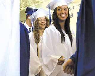 A Poland graduate with fist clenched walks past Lindsay Mitchell (left) and Katarina Meris (right) on his way to receive his diplomia holding a penny that he tried to drop into the principals palm during a handshake at Poland's 2010 Commencement Ceremony at the high school gymnasium on Sunday afternoon. Pennies could be heard hitting the floor throughout the ceremony as students backed out of the practical joke and the principal refused to accept the comical offering.
