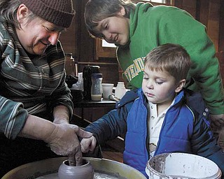 Vendor, Mary Bobersky (left), of Lake Milton, demonstrates how to shape pottery for her nephew, James Auden (back right), 11 also of Lake Milton, and Jackson Spin, (front right) 2 of Boardman, during the Millcreek Holiday event at Lanterman's Mill on Sunday afternoon.