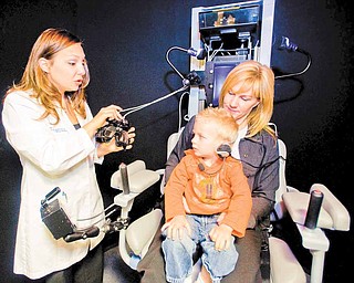 Dr. Cara Makuta, left, gets the goggles ready for Casey Ecker, 3, as he sits on the lap of his mother, Heidi Brandl, of Newport Beach, California, before being tested by Dr. Cara Makuta, in the Neuro Kinetics Rotational chair, which helps evaluate overall inner ear functions.