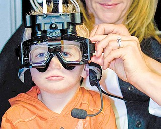 Casey Ecker, 3, has  goggles adjusted as he sits on the lap of his mother, Heidi Brandl, of Newport Beach, California, before being tested by Dr. Cara Makuta, in the Neuro Kinetics Rotational chair, which helps evaluate overall inner ear functions. 