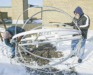 Al Nagy, right, a retired Youngstown Street Department employee, and Mickey Koziorynsky, Street Department supervisor, prepare the city’s New Year’s Eve ball on the roof of the City Hall Annex building. The ball, which will receive a covering later, will drop at midnight as part of the First Night Youngstown celebration.