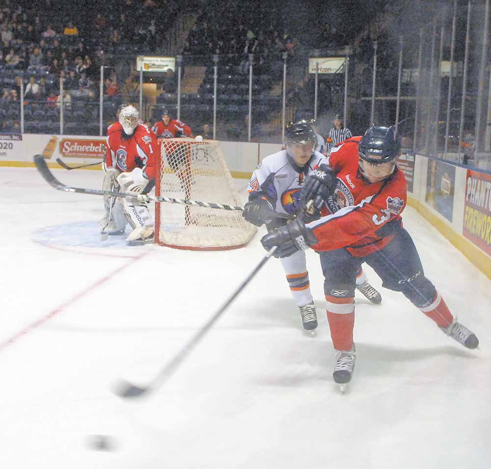 Conner Kucera of the Des Moines Buccaneers fights for possession of the puck against Phantom Ty Loney.