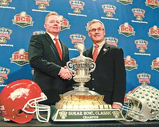 Ohio State head coach Jim Tressel, right, and Arkansas head coach Bobby Petrino, left, shake hands in front of the Sugar Bowl trophy for the upcoming NCAA football BCS bowl game in New Orleans, Monday, Jan. 3, 2011.