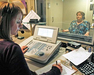 Audiologist Rebecca Price, left, tests the threshold of hearing a special tone over white noise, as Teri Kim, in a soundproof booth, responds by pushing a button at Duke Hospital's Department of Speech Pathology and Audiology in Durham, North Carolina.