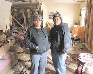 Angel Johnson, left, and her husband, Christopher Reynolds stand in what is left of their living room at 1630 Deerfield Ave. SW, Warren, Wednesday morning. While they were away on Tuesday afternoon, a
vehicle being driven by a Youngstown man who had just been shot in the chest drove through the front of the house and nearly out the back. The one-story house might be a total loss, but they can only
imagine the tragedy that would have occurred if they and their two small children had been home. Behind them to the right is where the home office and computer desk was. To the left was the bathroom and hallway.