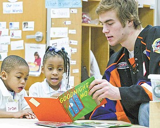 Youngstown Phantoms hockey player Matt O’Connor reads to Millcreek Children’s Center students Jor’Den Young and Monica Cash, both 3, during a visit Thursday. Members of the team read to kids, distributed stuffed animals and presented a $500 check to the center from the BJ Alan Corp.