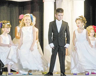 Christopher McMahan, 7, of Niles models a ring bearers Tuxedo while flower girls model dresses during Evaline's Bridal show Sunday at Covelli Center