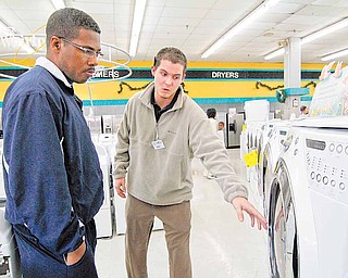 In this Dec. 24, 2010 photograph Cowboy Maloney's Electric City sales associate Bennett Chandler, right, shows off the features of a new front loading dryer to Noel Freeman of Terry, Miss., during a visit to the appliance store in Jackson, Miss. The U.S. economy ended last year on an encouraging note, with all parts of the country showing improvements. Factories produced more, shoppers spent more and companies hired more. All those signs point to a stronger economy in 2011.