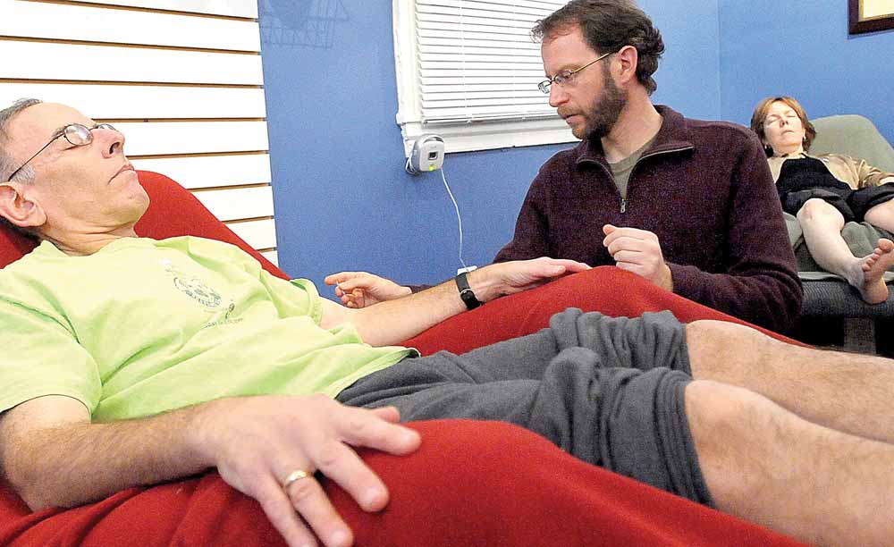 Fred Wolfson, owner of "Acupuncture For All" treats several patients at a time in a peaceful, communal room, which keeps the costs down to what a normal acupuncture procedure costs. Here, Wolfson, center, treats Ron Freeman with acupuncture needles, December 14, 2010, in Baltimore, Maryland. 