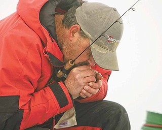Ice Fishing is cool - water and cold weather are detrimental to equipment as John Walczak of Campbell blows on his reel to unfreeze the line.