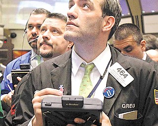 In this file photo taken Jan. 10, 2011, trader Gregory Rowe, right, works with fellow traders on the floor of the New York Stock Exchange.