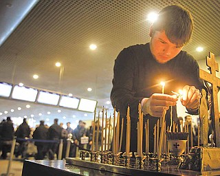 A clergyman lights candles at a site of a blast at Domodedovo airport near Moscow on Wednesday, Jan. 26, 2011. Security was tightened in Moscow on Tuesday, after a suicide bomber set off an explosion that ripped through Moscow's busiest airport on Monday.