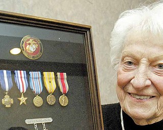 Suzanne Johnson McLaughlin holds  a display of her late husband Charles Johnson's war medal. He was posthumously awarded the Navy Cross.