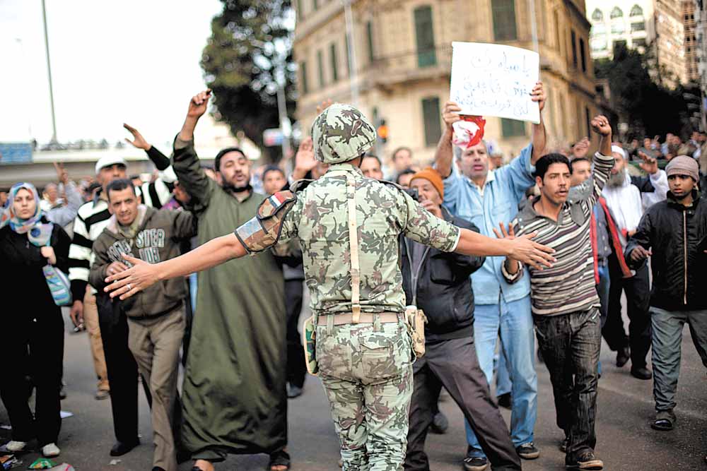 An Egyptian army soldier tries to stop anti-government protesters as they walk towards Tahrir Square in Cairo, Sunday, Jan. 30, 2011. The Arab world's most populous nation appeared to be swiftly moving closer to a point at which it either dissolves into widespread chaos or the military expands its presence and control of the streets.  