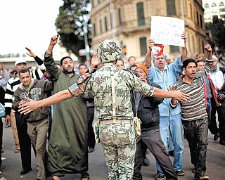 An Egyptian army soldier tries to stop anti-government protesters as they walk towards Tahrir Square in Cairo, Sunday, Jan. 30, 2011. The Arab world's most populous nation appeared to be swiftly moving closer to a point at which it either dissolves into widespread chaos or the military expands its presence and control of the streets.  