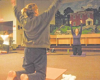 Jennifer Neal, background right, leads a yoga class in a stretching exercise at Liberty Township Administration Building, 1315 Church Hill-Hubbard Road. Sessions are at 7 p.m. Sundays. The other two women are unidentified. Candles and music of singing bowls and healing bells set the mood for an evening to uplift the body and soul.