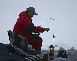 ROBERT K. YOSAY | THE VINDICATOR..Ice Fishing is cool - fresh catch as John Walczak of Campbell pulls out a crappie from Mosquito Lake . Aids such as lanterns, ice  houses, heaters, fishfinders are common.... Ó--30-..