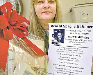 Cindy Michael, who founded the Lena, Mason, Christian Foundation to remember the three murder victims, holds a flyer for a benefit spaghetti dinner on Saturday that will feature a basket raffle. The dinner funds projects that help children.
