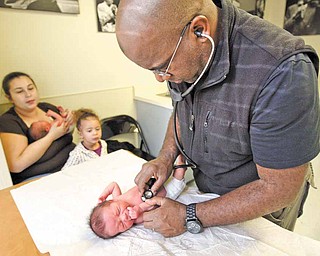 Pediatrician Dr. Gary Bean, right, examines one of two one-week-old twins, Emanuel Newell III, as mom Dawn Hinkle holds the other twin Samarah Newell and watches with daughter Saniyah Newell, 2, during the twins' checkup in Oakland, California, January 14, 2011.