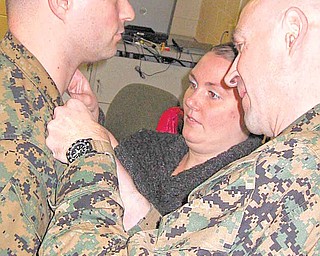 At right, Marine Lt. Col. William J. Truax, officer-in-charge of coordination, liaison and assessment team Latin America, Fort Story, Va., and Amanda Rudolph, put on Gunnery Sgt. Robert A. Rudolph, of Youngstown, the pin to his current rank. Amanda is Rudolph’s wife.