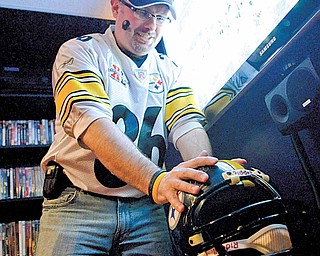 Jim Davis rubs a Steelers helmet in his Austintown basement for good luck. The helmet is signed by four members of the Steel Curtain Steelers teams. The Steelers scored their first touchdown of the night minutes later but eventually lost the game.