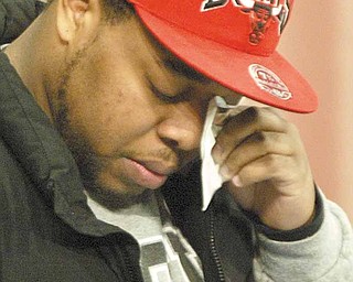 YSU student Adrian Watson wipes away a tear before reading a poem during a prayer service on campus Monday. Watson was friends with Jamail Johnson, the man killed in the weekend shooting at an off-campus party. He wrote the poem for his late friend.