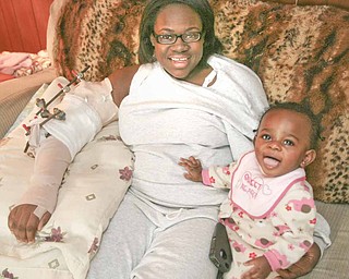 Jaleesa Moore sits with her daughter, Olivia, 9 months, inside her Girard home. Moore was shot in the side and elbow early Sunday while attending a party near the Youngstown State University campus where she is a sophomore. Another student was killed. The bones in her elbow had to be surgically reconstructed.