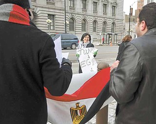 Salam Elwanni of Youngstown holds a sign referring to the recent revolutions in Tunisia and Egypt and speculating on which country could protest for its freedom next. She was among about 40 demonstrators celebrating the departure of Hosni Mubarak as Egypt’s president at a downtown Youngstown rally Friday in front of the Lambros Federal Building and U.S. Courthouse on Market Street. In the background is the Mahoning County Courthouse.
