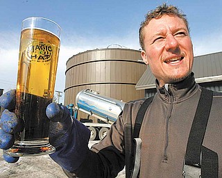 In this Jan. 26, 2011 photo, Eric Fitch holds a Magic Hat glass in front of the digester building at the brewery in South Burlington, Vt. The Vermont brewery is giving new meaning to the idea of green beer. Magic Hat Brewing Co., of South Burlington, is the first site to use a device that turns spent grain from the brewing process into natural gas that is then used to fuel brewing operations. The 42-foot tall anaerobic methane digester, installed last summer, extracts energy from the spent hops, barley and yeast left over from the brewing process.