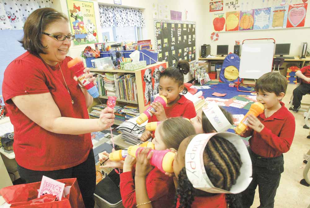 Teacher Andrea McGoogan and a group of her first-graders talk into toy microphones during a Valentine’s Day party in their room Monday. The microphones were a present to each child from McGoogan.