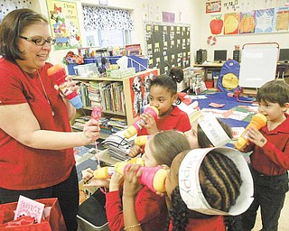 Teacher Andrea McGoogan and a group of her first-graders talk into toy microphones during a Valentine’s Day party in their room Monday. The microphones were a present to each child from McGoogan.