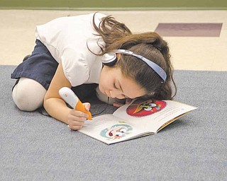 Makenna Ploessel, 6, uses a Leapfrog electronic pen and headphones to make her way through a book, using both audible and visual cues to learn. Makenna is in kindergarten in Jessica Redmond’s class at Taft Elementary School in Youngstown. The device is one of the educational materials Redmond received after collecting donations online through DonorsChoose.org. The website allows teachers to post the projects or materials they’re requesting and allows people to contribute to them.