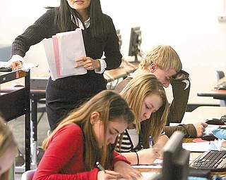 Siao looks on as students in her seventh-grade class practice writing characters in Chinese. From front to back are Canfield Village Middle School students Nikki Tuchek, Paige Modareli and Nick Sammarco.