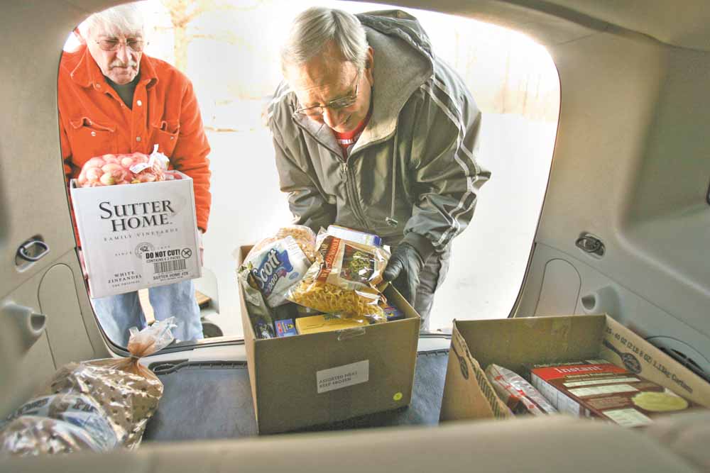 Bob Rose, left, and Gerald Rassega, load boxes of food from the Vienna Ecumenical Food Pantry on Warren-Sharon Road into the back of a car. The pantry is operated by three churches — Vienna United Methodist, Vienna Presbyterian, and St. Thomas the Apostle Catholic Church, formerly St. Vincent de Paul Church.