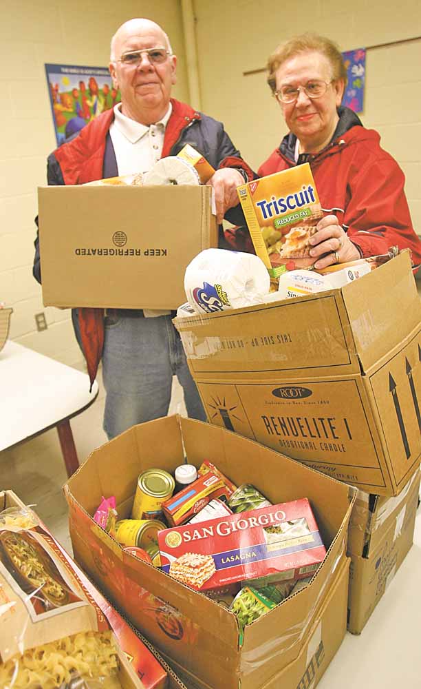 Joe and Ruth Hayes, who helped found the food pantry in 1985, pack food boxes for distribution. The pantry is located in St. Thomas the Apostle Catholic Church on Warren-Sharon Road in Vienna.