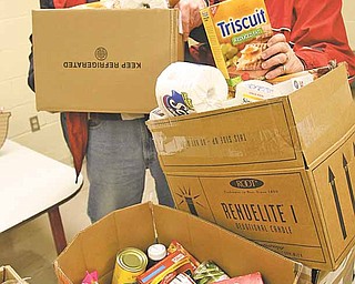 Joe and Ruth Hayes, who helped found the food pantry in 1985, pack food boxes for distribution. The pantry is located in St. Thomas the Apostle Catholic Church on Warren-Sharon Road in Vienna.