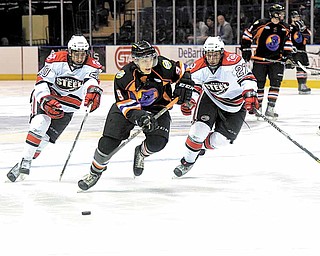 Youngstown Phantom Andrew Sinelli chases the puck down the ice while being pursued by the Chicago Steel's Jimmy Devito (20) and Peter Hand (27) .