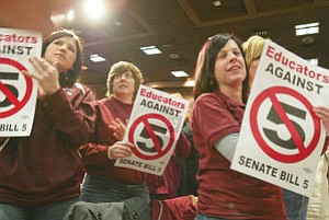 Members of the Boardman School Teachers Union cheer during Monday night’s rally against Senate Bill 5 at Youngstown State University.  From left Paula Ritter, Allison Morgan, Sharon Tomcsanyi (hidden) and Kate Cretella hold signs and applaud. The public forum drew more than 1,200 people.