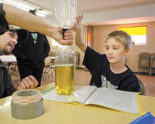 Mason Harding, 11, a fifth-grade student at Youngstown’s William Holmes McGuffey Elementary School, gets help from his uncle, Justin Harding, on his project, a vortex that mimics a tornado, that Mason will present at the upcoming science fair at Youngstown State University.