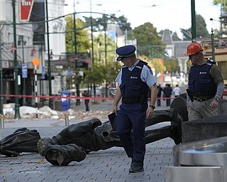 Two police officers walk past a fallen statue in Christchurch, New Zealand , Thursday, Feb. 24, 2011 while doing a patrol after the city was hit by a 6.3 magnitude earthquake on Tuesday. Hundreds of troops, police and emergency workers raced against time and aftershocks that threatened to collapse more buildings. They picked gingerly through the ruins, poking heat-seeking cameras into gaps between tumbles of bricks and sending sniffer dogs over concrete slabs.