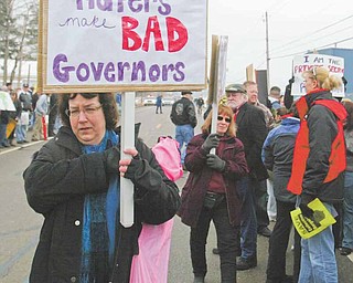 Wendy Clagett, a teacher in the Mathews school district, carried a sign and joined a group of protesters outside the Youngstown-Warren Regional Airport in Vienna, where Gov. John Kasich spoke.