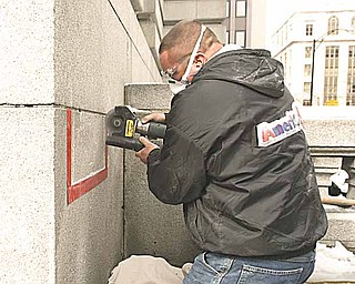 Steve Kibbler of Ameriseal uses a saw to cut the granite cornerstone at the Mahoning County Courthouse and retrieve a time capsule. The time capsule will be opened Friday afternoon.
